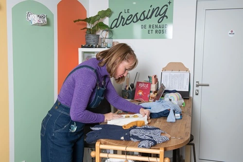 image de l'intérieur de la boutique, Gwenoline controlle un vêtement, plan large